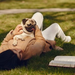 Woman in a spring park. Girl with cute pug. Brunette with a dog.